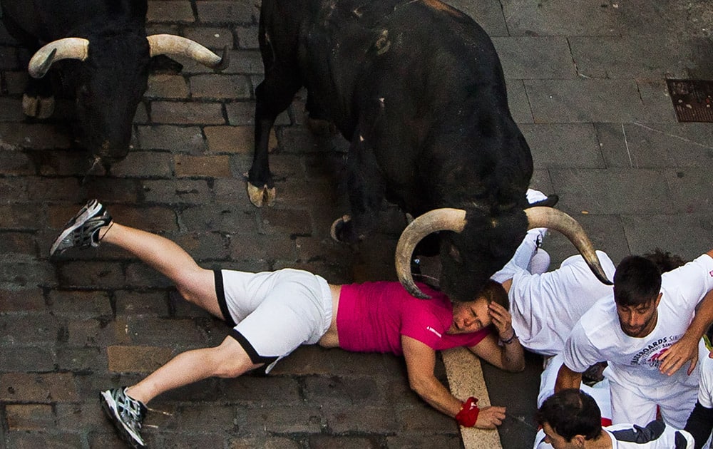 Victoriano del Rio fighting bulls run over revelers during the running of the bulls, at the San Fermin festival, in Pamplona, Spain.