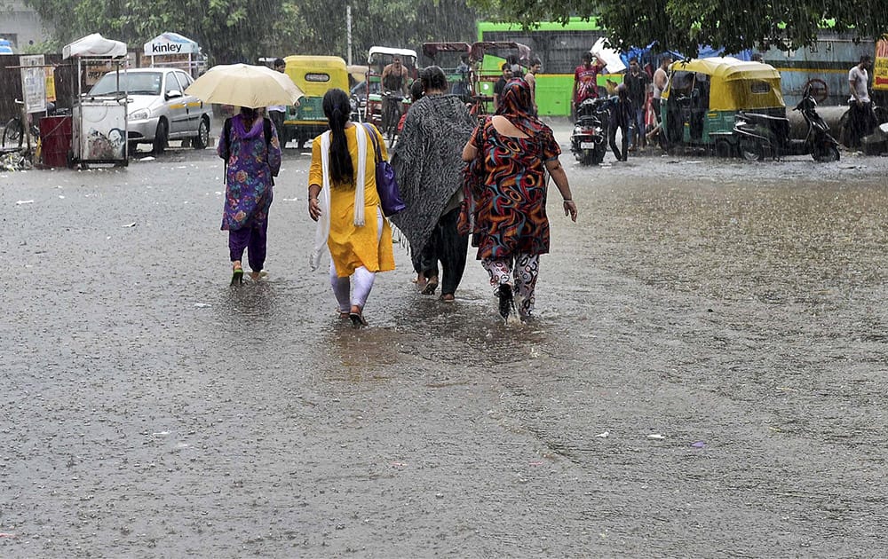 People walk on a water logged street in New Delhi.