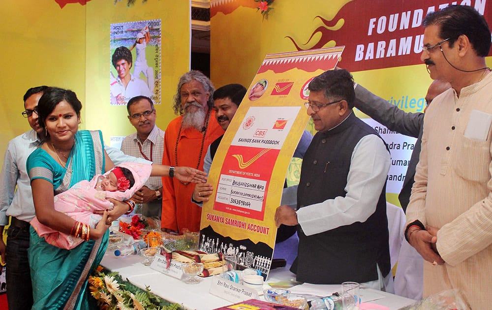 Union Communication and IT Minister Ravi Shankar Prasad with Petroleum Minister Dharmendra Pradhan presenting Sukanya Samridhi account to a one month old baby girl during a function in Bhubaneswar.