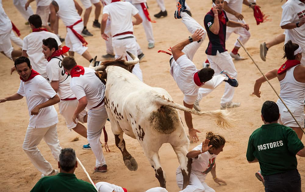 A runner is knocked by a steer during the second running of the bulls at the San Fermin Festival, in Pamplona, Spain.