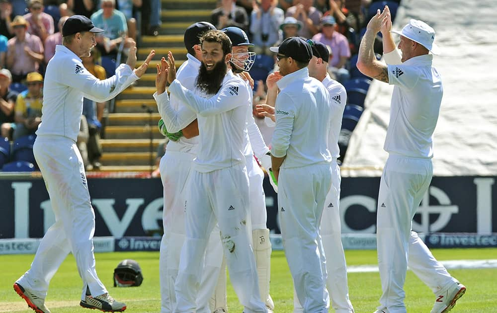 England’s Moeen Ali celebrates with teammate Joe Root after bowling Australia’s Steve Smith caught Alastair Cook for 33 runs during day two of the first Ashes Test cricket match, in Cardiff, Wales.