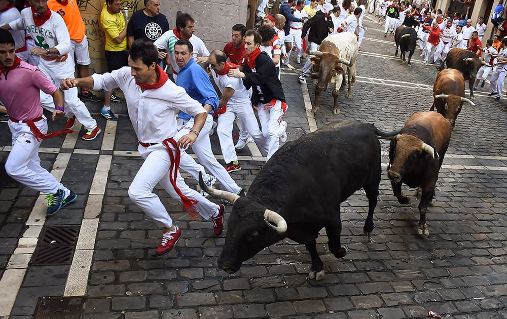 Participants go to take Estafeta corner running beside to ''Fuente Ymbro'' fighting bulls during the fourth running of the bulls, at the San Fermin Festival, in Pamplona, Spain.