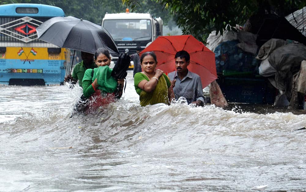 People wade through a water logged road after heavy rains in Kolkata.