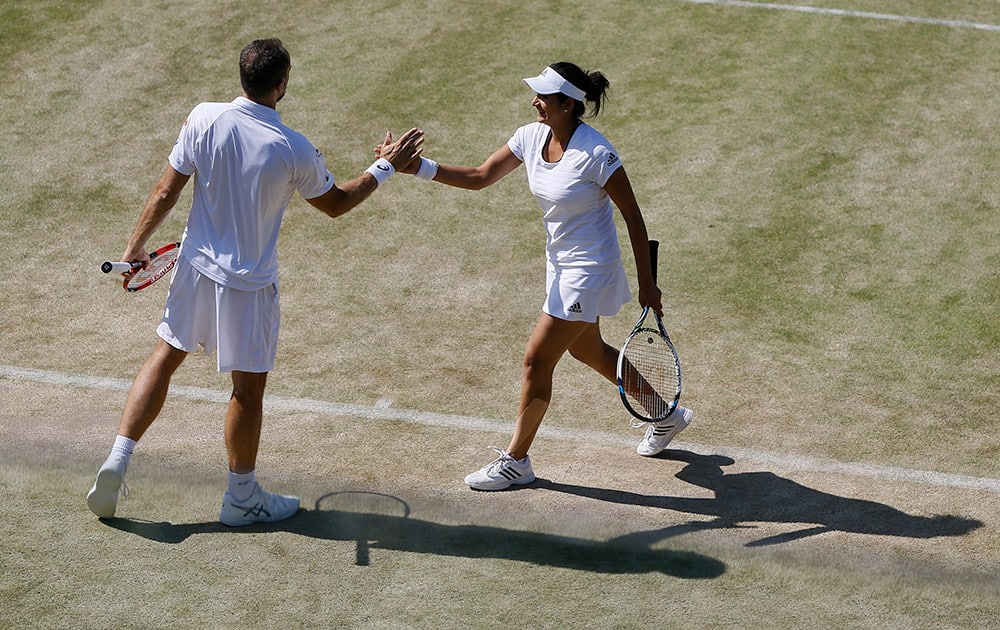 Bruno Soares of Brazil and Sania Mirza of India talk between points during the mixed doubles quarterfinal match against Alexander Peya of Austria and Timea Babos of Hungary at the All England Lawn Tennis Championships in Wimbledon, London.