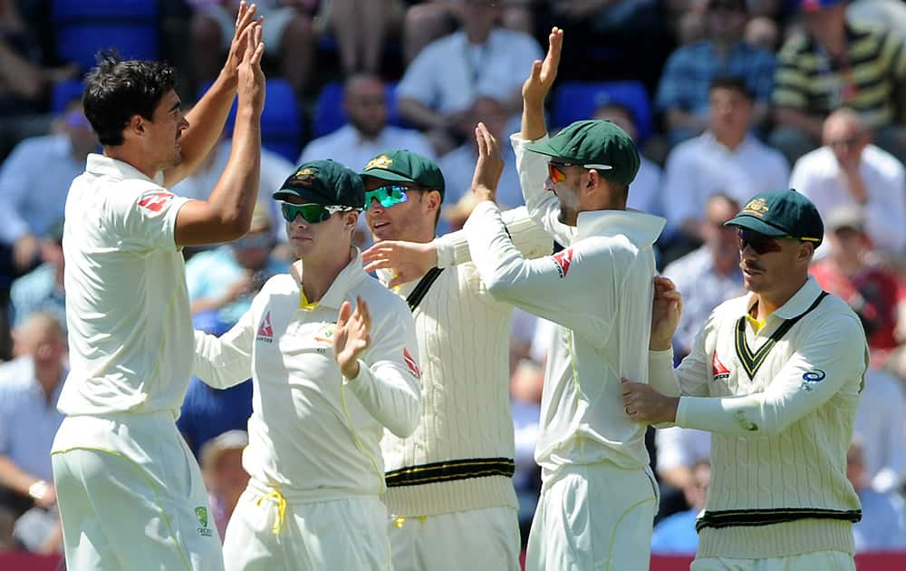 Australia’s Mitchell Starc celebrates with teamates after bowling England's Alastair Cook caught Nathan Lyon for 12 runs during day three of the first Ashes Test cricket match, in Cardiff, Wales.