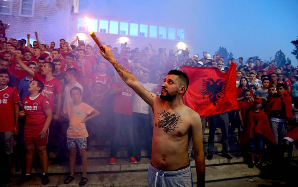 An Albanian with a tattooed eagle national symbol on his chest holds a flare torch while thousands of fans sing and dance at Mother Teresa Square in central Tirana to celebrate the three points awarded to Albania over Serbia by the top sports court, Tirana.