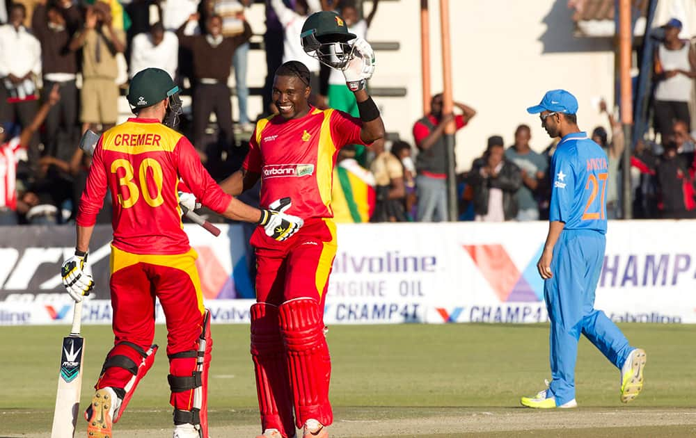 Zimbabwean captain Elton Chigumbura, centre, celebrates with fellow batsman Graeme Cremer after scoring 100 runs during the One Day International against India in Harare, Zimbabwe.