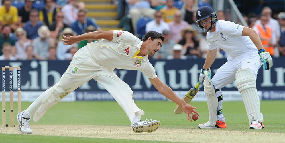 Australia’s Mitchell Starc, left, reaches for the ball watched by England's Jos Buttler during day three of the first Ashes Test cricket match, in Cardiff, Wales.