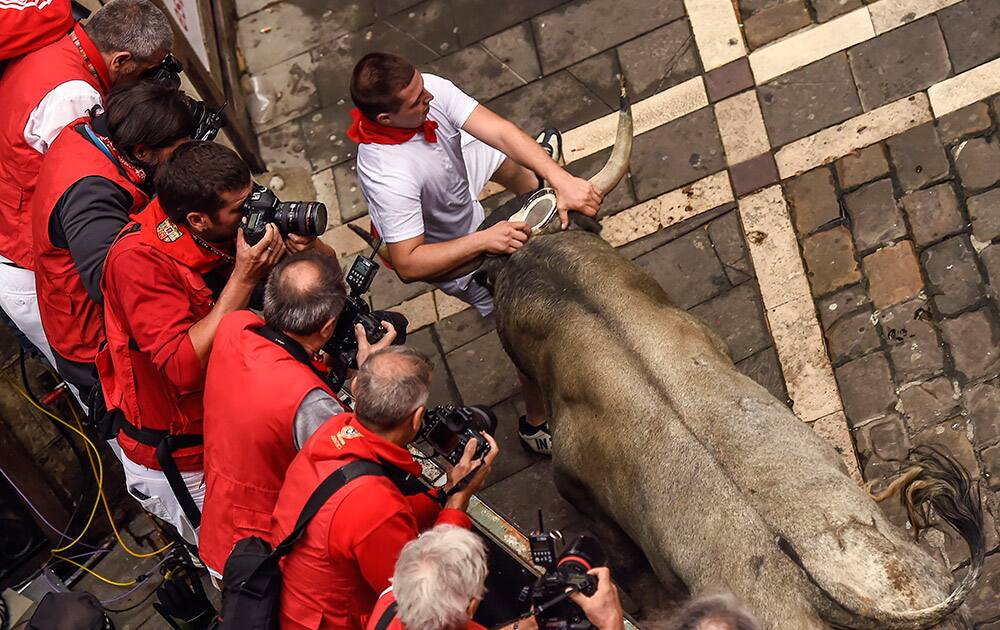 A participant tries to protect himself of ''Jose Escolar Gil'' fighting bull alongside Estafeta corner, during the fifth running of the bulls, at the San Fermin Festival, in Pamplona, Spain.
