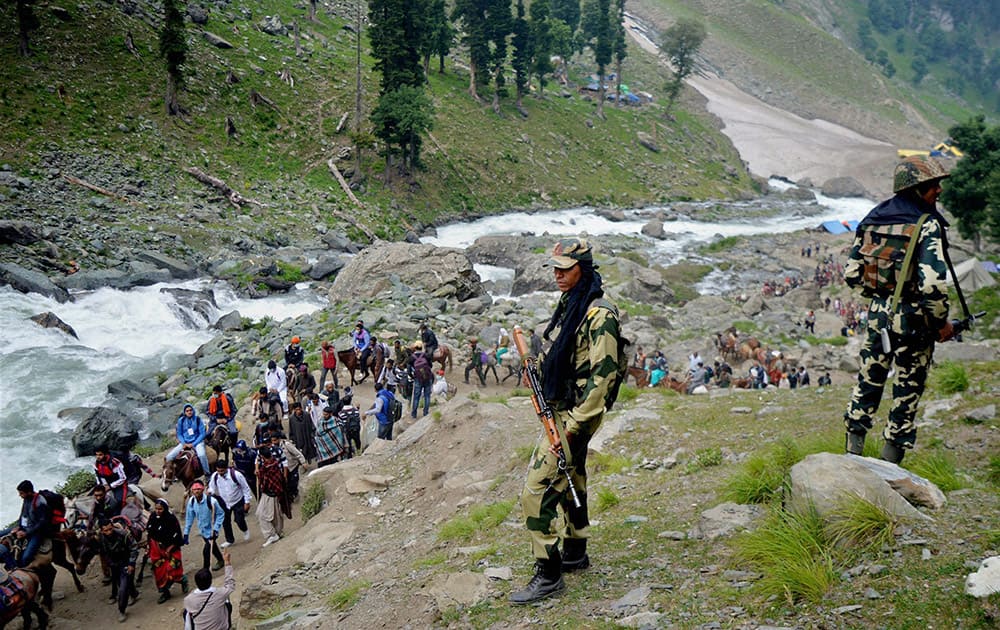 CRPF personnels stand guard as Pilgrims cross the mountains as they move towards Amarnath Holy Cave Shrine 3880 meters high, during the10th batch to their religious journey via Chandanwari route, some 115 kilometers southeast of Srinagar.