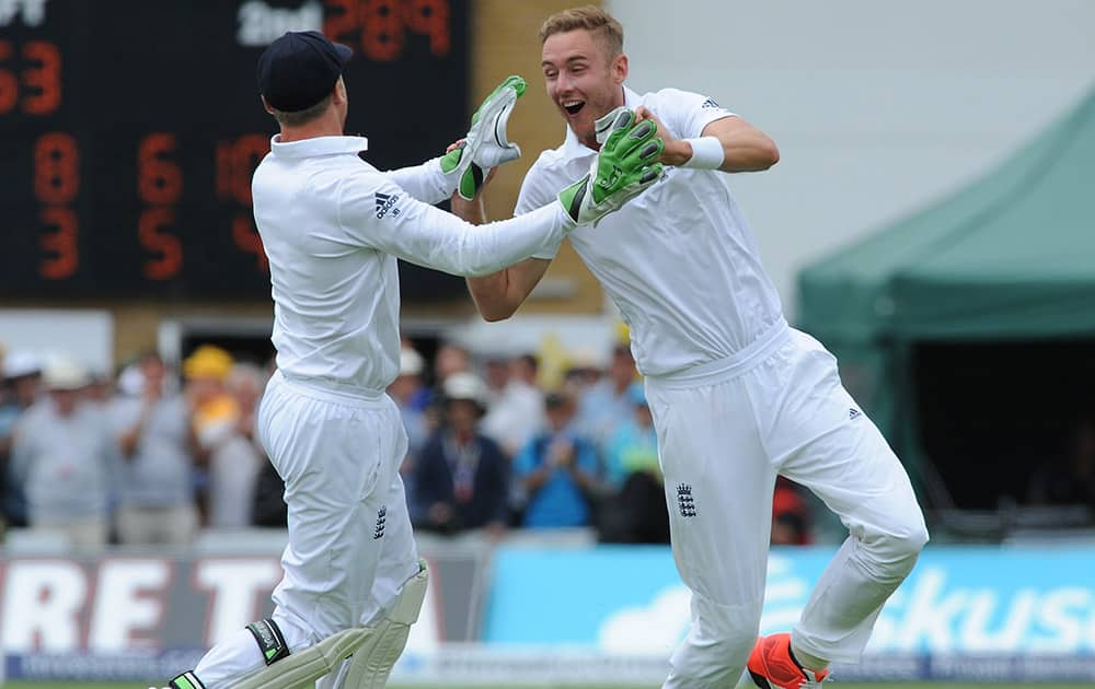 England’s Stuart Broad celebrates with Jos Buttler after bowling Australia’s Steve Smith caught Ian Bell for 33 runs during day four of the first Ashes Test cricket match, in Cardiff, Wales.