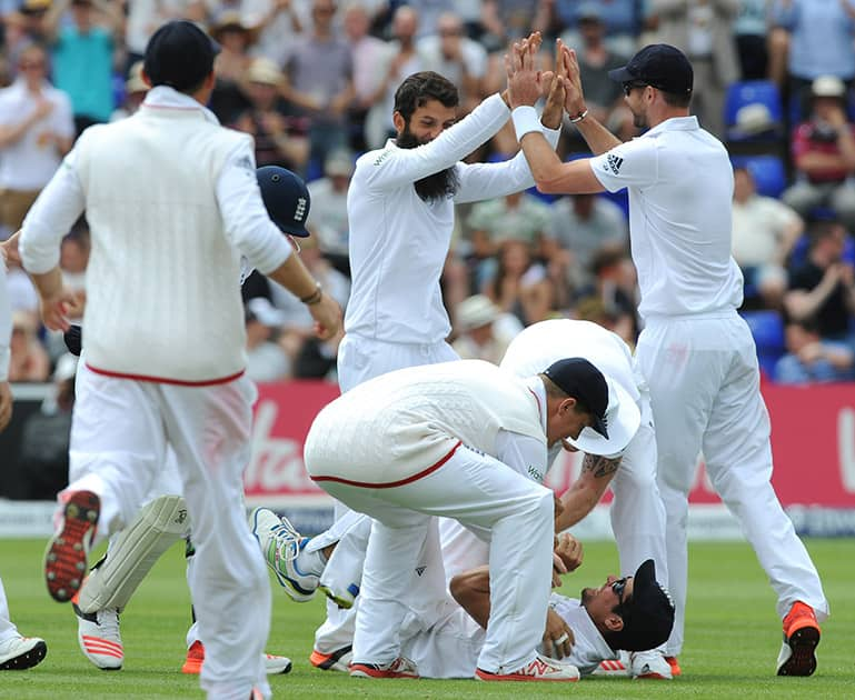 England’s Moeen Ali celebrates with James Anderson after bowling Australia’s Brad Haddin caught England’s Alastair Cook for 7 runs during day four of the first Ashes Test cricket match, in Cardiff, Wales.