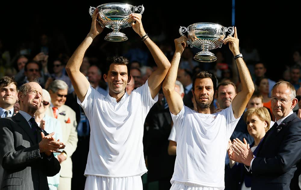 Horia Tecau of Romania, left, and Jean-Julien Rojer of the Netherlands lift the trophies after winning the men's doubles final against Jamie Murray of Britain and John Peers of Australia at the All England Lawn Tennis Championships in Wimbledon, London.