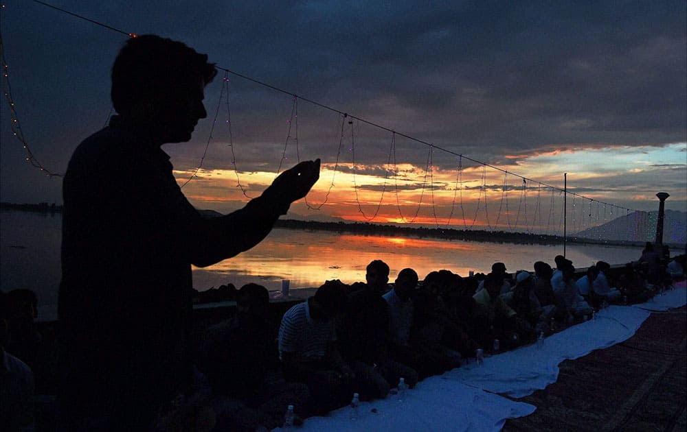 A man prays as he waits for iftaar (breaks fast) to set a record of Asias Longest Iftaar,on the Banks of Dal Lake in Srinagar.