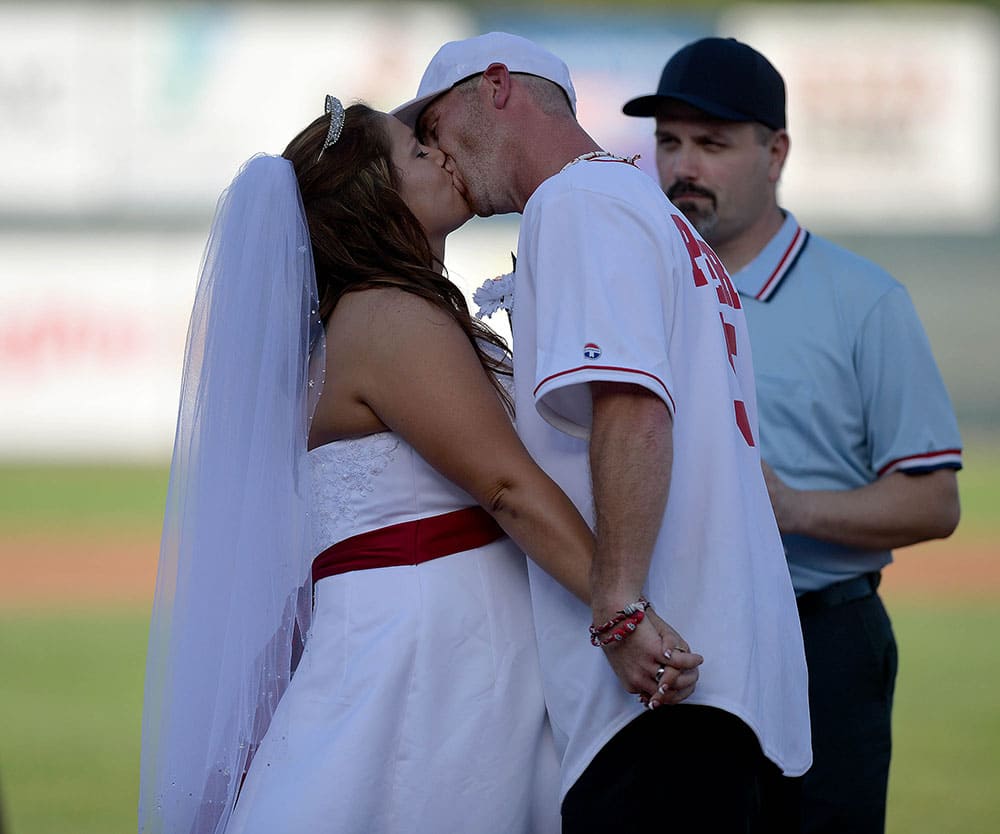 Morgan Reynolds is kissed by her husband Jason Peters as the couple said their vows at home plate in a baseball themed wedding, at Phil Welch Stadium in St. Joseph, Mo.