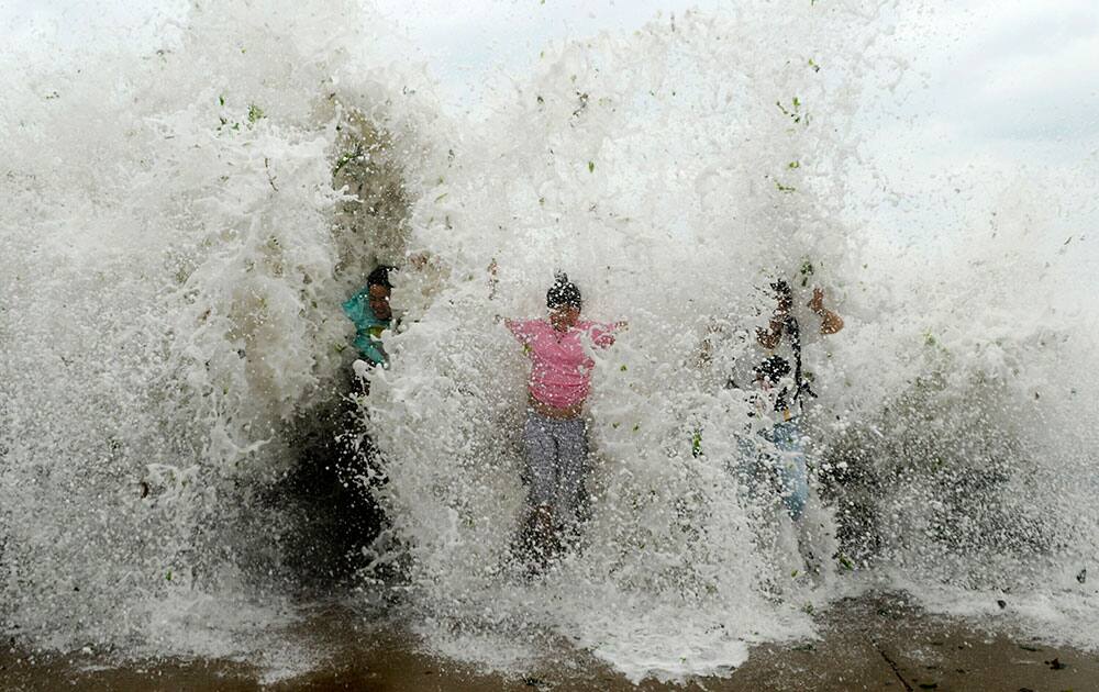 People are splashed by sea waves strengthened by Typhoon Chan-hom at the seacoast of Qingdao in east China's Shandong province.