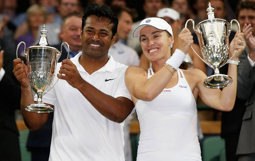 Leander Paes of India, left, and Martina Hingis of Switzerland hold up the trophies after winning the mixed doubles final against Alexander Peya of Austria and Timea Babos of Hungary at the All England Lawn Tennis Championships in Wimbledon, London.