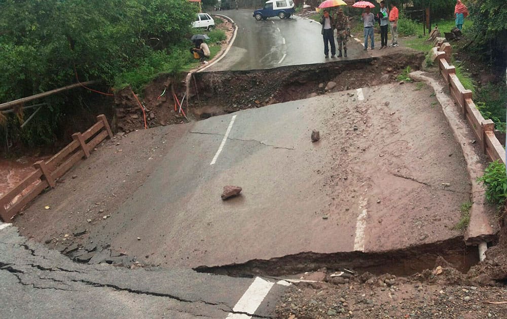 People look at a bridge that collapsed due to heavy rainfall at Nagesh in Rajouri.