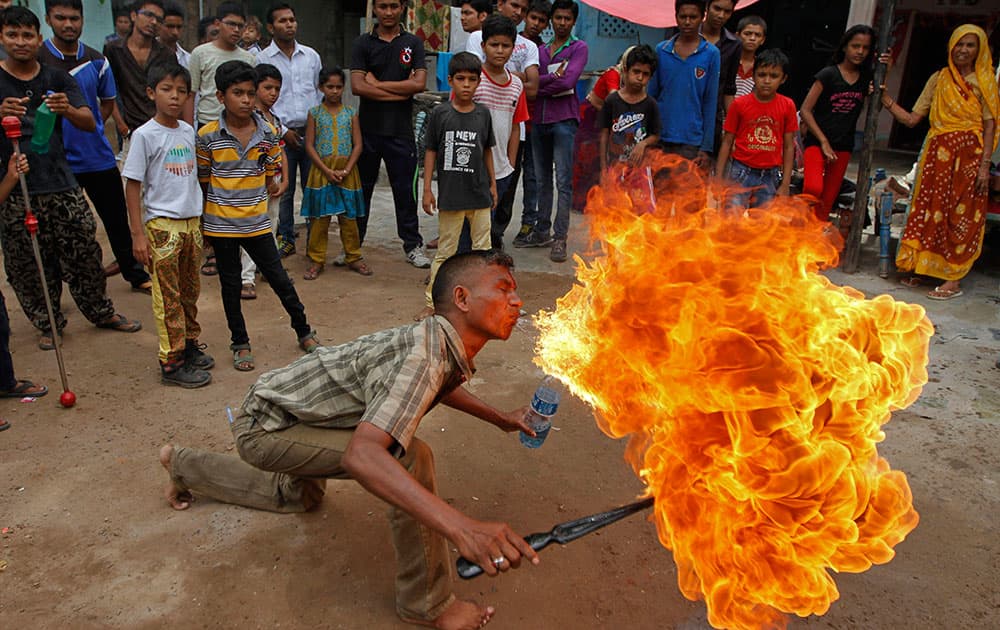 Residents gather to watch as an Indian man displays his fire stunt skills before media in Ahmadabad, India