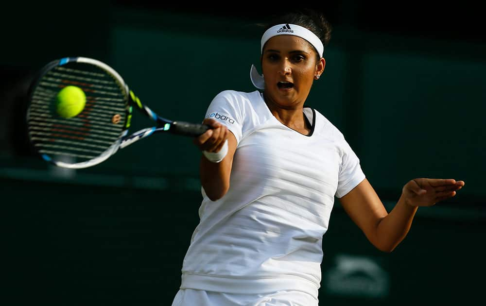 Sania Mirza of India plays a return during the women's doubles final between Martina Hingis of Switzerland, and Mirza, against Ekaterina Makanrova of Russia and Elena Vesnina of Russia at the All England Lawn Tennis Championships in Wimbledon, London.