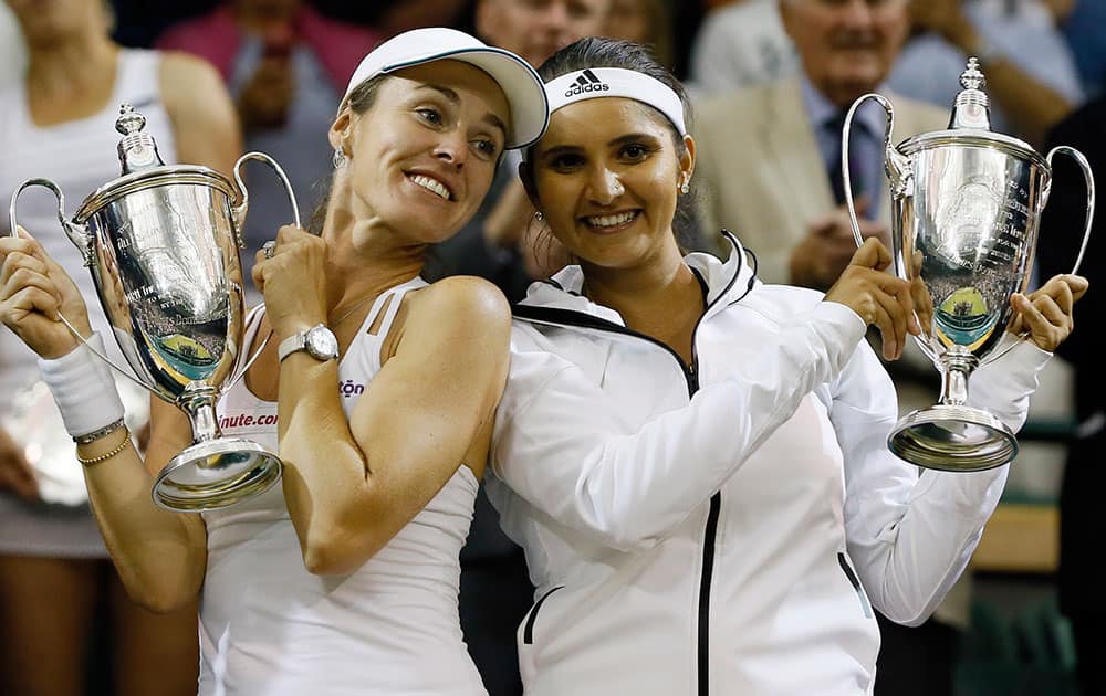 Martina Hingis of Switzerland, left, and Sania Mirza of India hold their trophies after winning the women's doubles final against Ekaterina Makarova of Russia and Elena Vesnina of Russia at the All England Lawn Tennis Championships in Wimbledon, London.