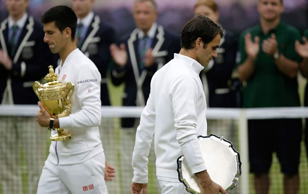 Novak Djokovic of Serbia, left, and Roger Federer of Switzerland hold their trophies after Djokovic won the men's singles final at the All England Lawn Tennis Championships in Wimbledon, London.