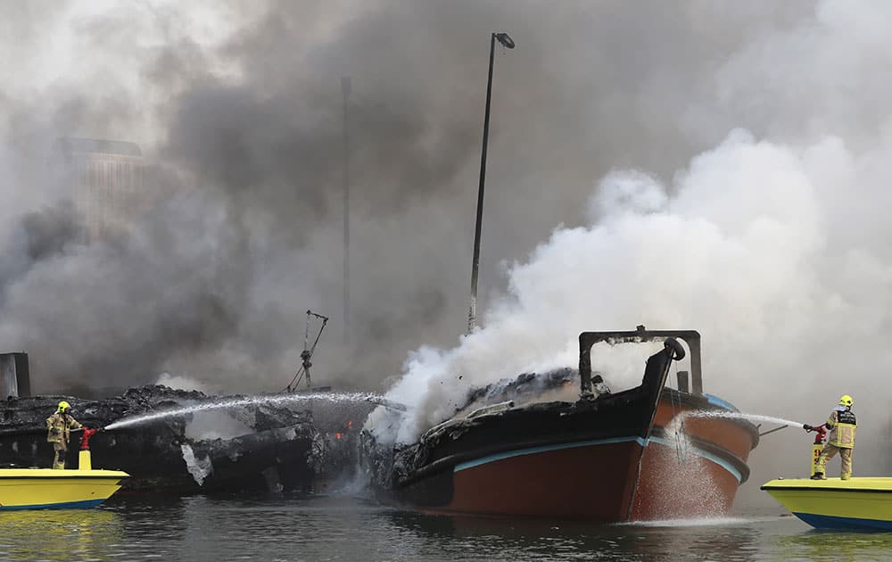 Smokes rise from two trading dhows as firefighters spray water to distinguish the fire at the Dubai creek, in Dubai, United Arab Emirates. 