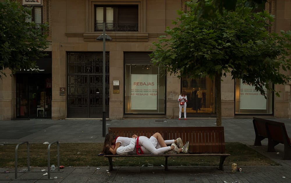 Revelers kiss in a bench before the daily morning running of the bulls of the San Fermin festival in Pamplona, Spain.