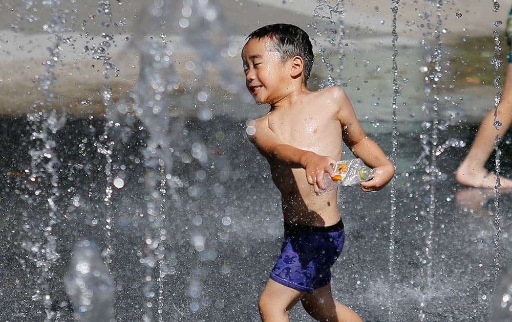 A boy plays in the water from sprinkler at a shopping complex in Tokyo.