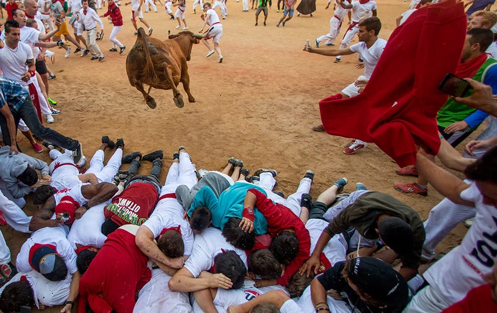 A cow jumps over revelers during a cow show in the bull ring, at the San Fermin Festival, in Pamplona, Spain.