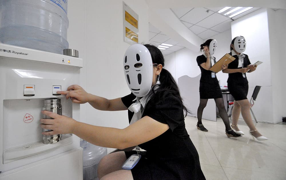 Staff wearing masks during a work day at a property service company specializing in leased office space in Handan in northern China's Hebei province. The company holds a monthly relaxation day at the office using various themes such as a 