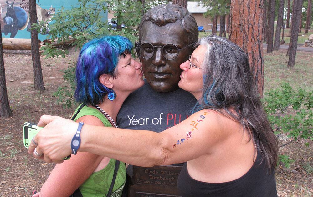 Trevor Tully, left, and Eva Marie Dragos, right, of Sedona, Ariz., kiss a bust of Clyde Tombaugh at Lowell Observatory in Flagstaff, Ariz.