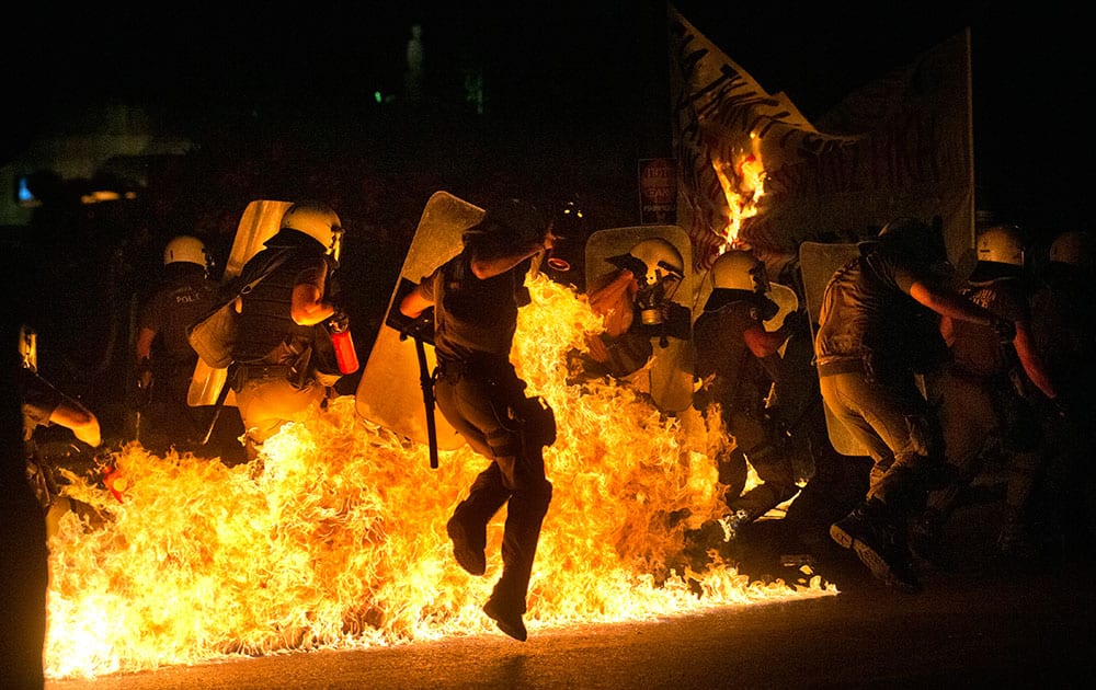 Riot police officers run through fire as anti-austerity protesters throw petrol bombs, during clashes in Athens.