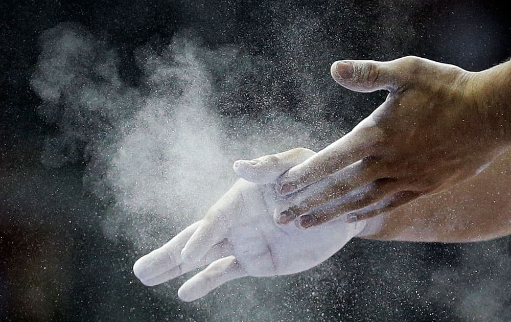 Brazil's Francisco Junior puts chalk on his hands during artistic gymnastics parallel bars competition in the Pan Am Games in Toronto.