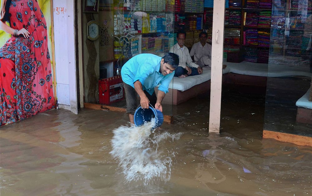 A shopkeeper removes water from his waterlogged shop after heavy rains in Varanasi.