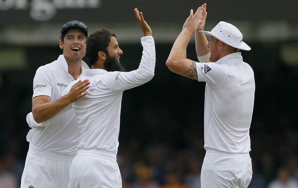 England's Moeen Ali celebrates with Alastair Cook and Ben Stokes after taking the wicket of Australia's David Warner on the first day of the second Ashes Test match between England and Australia, at Lord's cricket ground in London.