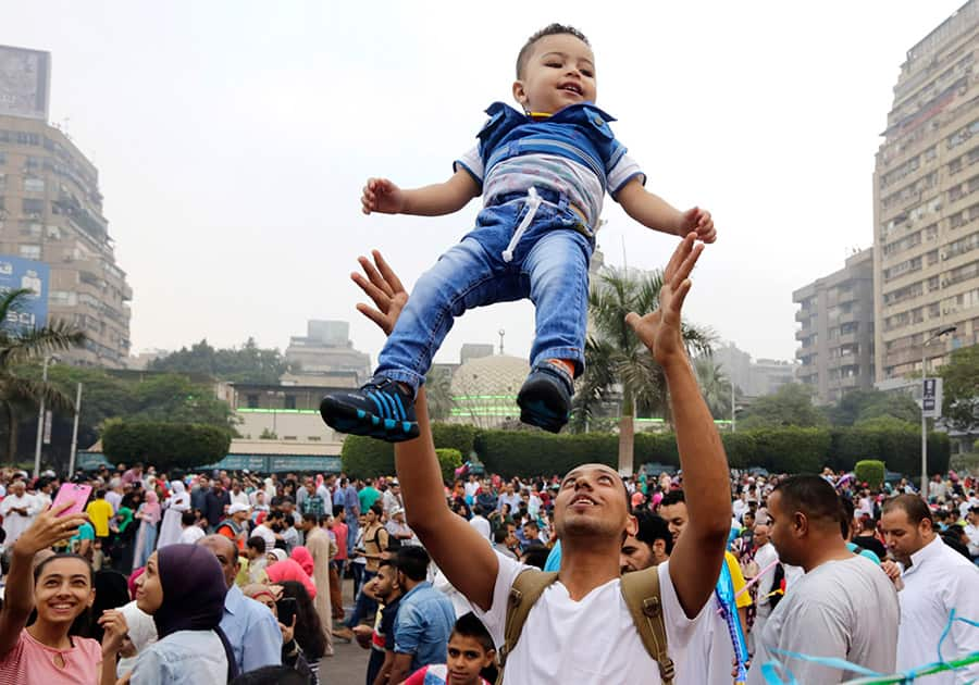 An Egyptian man tosses his son up in the air as people celebrate Eid al-Fitr feast, marking the end of the Muslim fasting month of Ramadan in Cairo, Egypt.