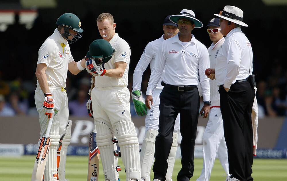 Australia's Chris Rogers, inspects his helmet with Steven Smith, left, after he was hit on the head by the first ball on the second day of the second Ashes Test match between England and Australia, at Lord's cricket ground in London.