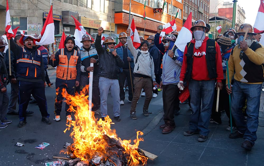 Miner waving Potosi department flags and chanting, stand around a burning barricade, during a protest demanding more resources for their region, in La Paz, Bolivia.