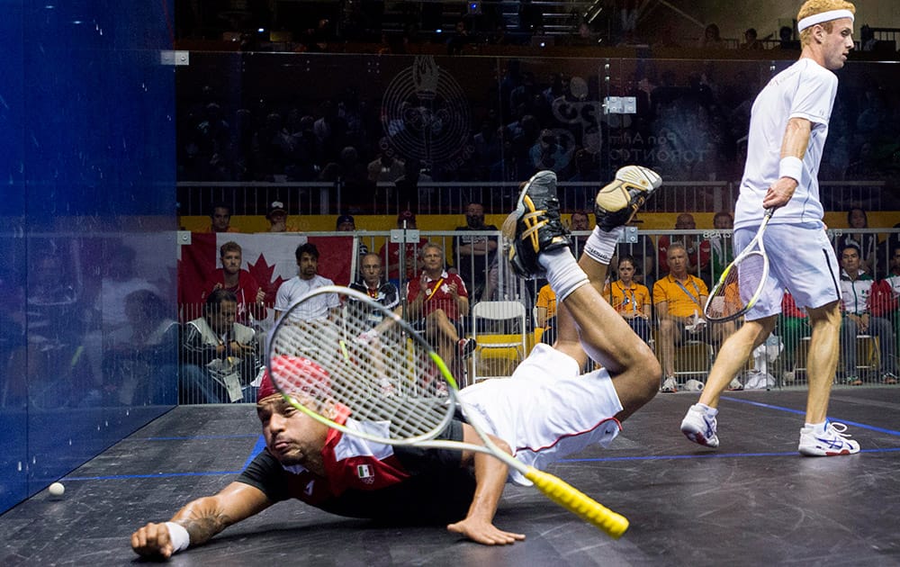 Mexico's Eric Galvez loses his racket as diving for the ball in front of Canada's Andrew Schnell during the men's team squash gold medal final at the Pan Am Games in Toronto. Canada defeated Mexico to win gold. 