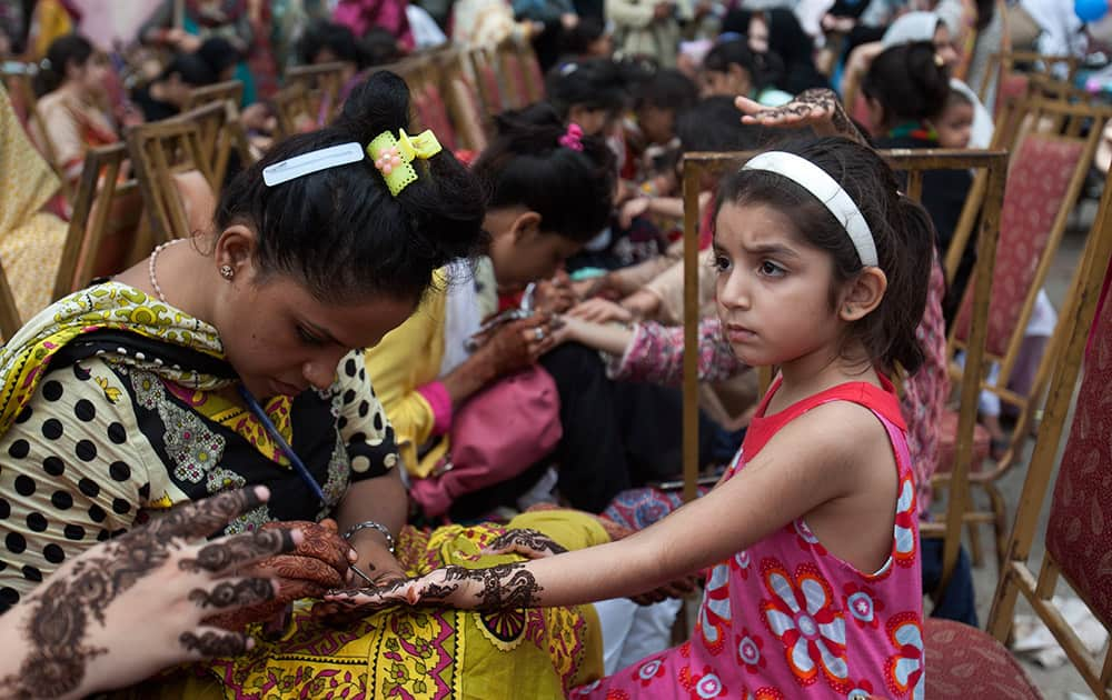 Pakistani beauticians paint the hands of customers with henna ink ahead of the Muslim Eid al-Fitr holiday to mark the end of the holy fasting month of Ramadan in Karachi, Pakistan.