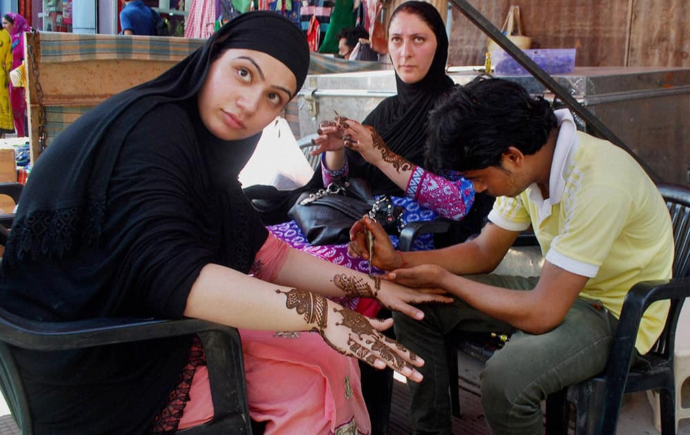 A Kashmiri girl getting her hand designed with Mehndi ahead of Eid-ul-fitr festival at Lal Chowk in Srinagar.