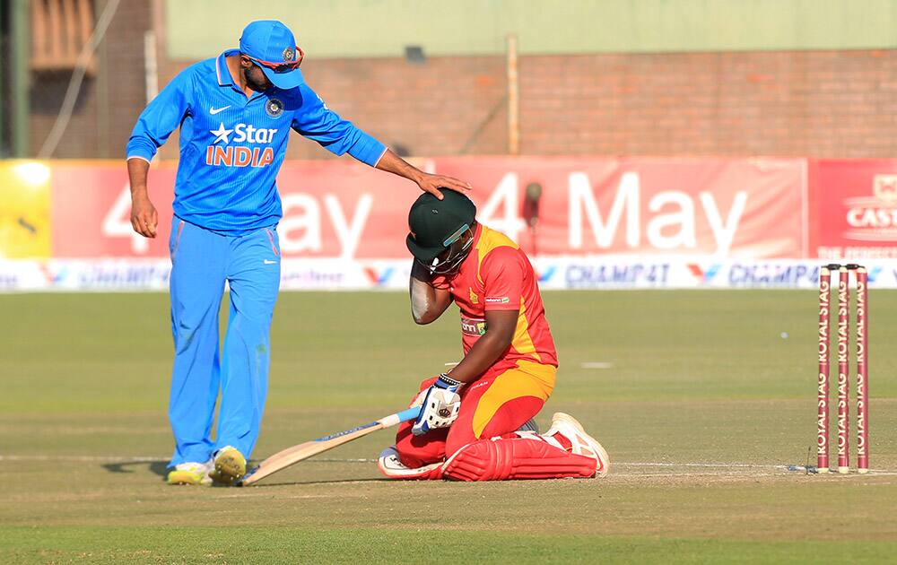 Ajinkya Rahane touches Zimbabwean batsman Prosper Utseya on the helmet after he fell to the ground in the Twenty20 cricket match against Zimbabwe in Harare, Zimbabwe.