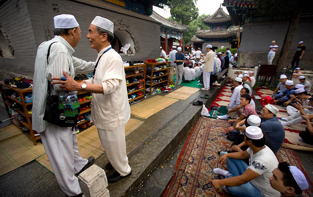 Liu Shoupeng, a Chinese Muslim and retired electrical engineer, greets an fellow worshiper before Eid al-Fitr prayers at Niujie Mosque, the oldest and largest mosque in Beijing.