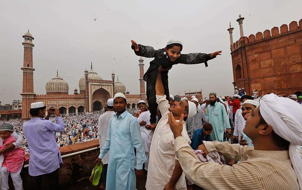 A man plays with his child after offering Eid al-Fitr prayers at Jama Masjid in New Delhi