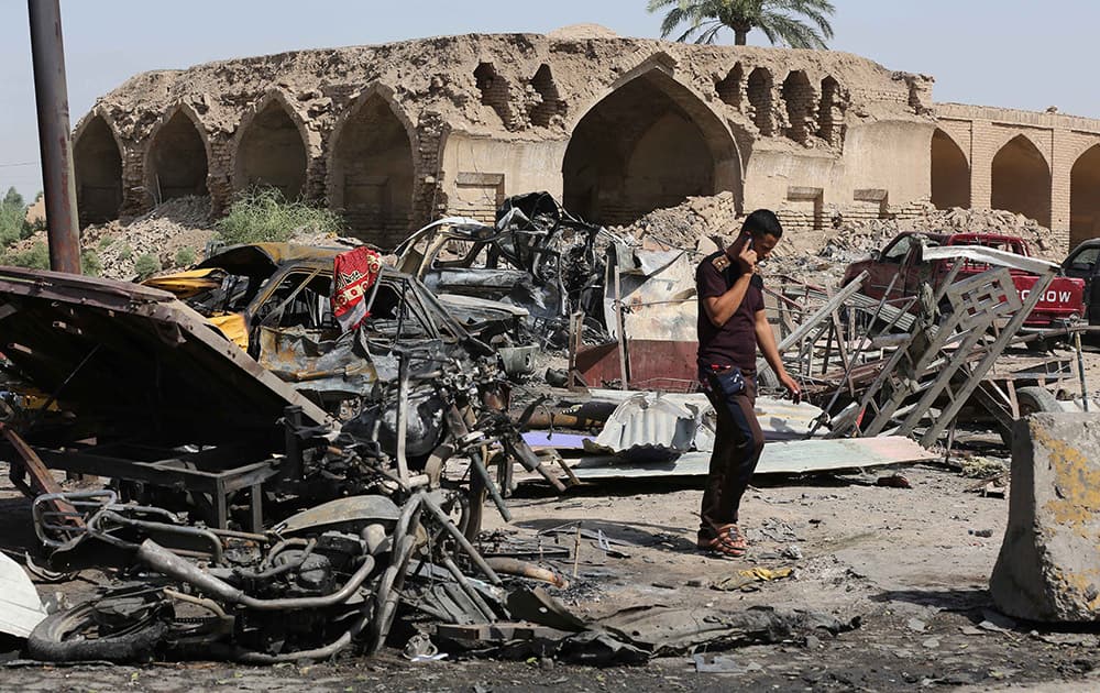 A civilian inspects the site of a deadly Friday night suicide car bombing at a busy market in Khan Beni Saad, about 20 miles (30 kilometers) northeast of Baghdad, Iraq.