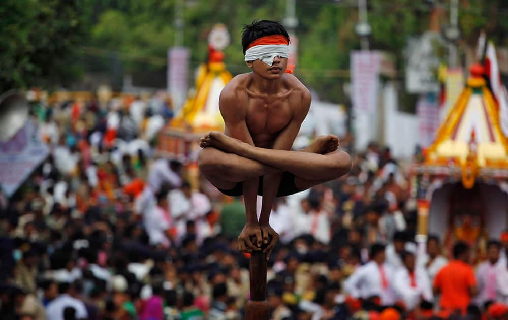 A boy practices Mallakhamb, a traditional Indian gymnastic sport on a vertical wooden pole during the annual Rath Yatra, or Chariot procession, in Ahmadabad.