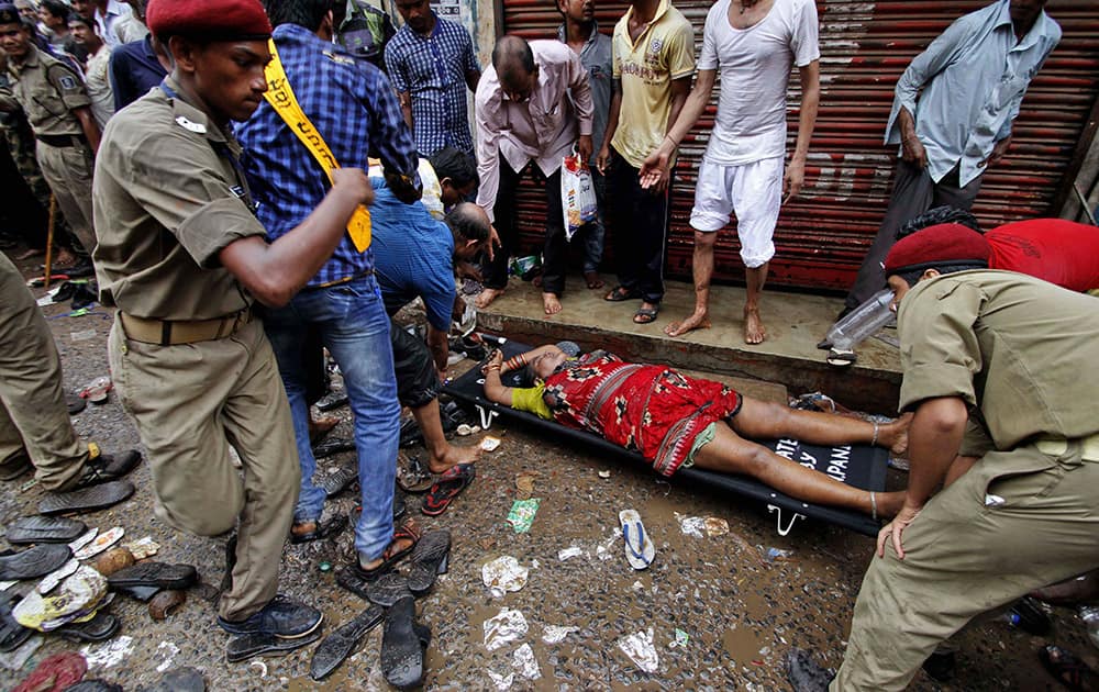 Policemen and local volunteers carry a woman on a stretcher, who fainted due to a stampede, as she is taken to a nearby hospital during the annual Rath Yatra or Lord Jagannath chariot procession in Puri.