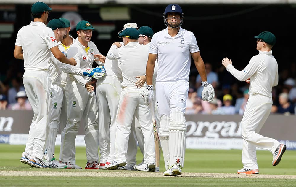 Australia's players celebrate as England's Alastair Cook leaves the pitch after he is bowled by Australia's Mitchell Marsh on the third day of the second Ashes Test match between England and Australia, at Lord's cricket ground in London.