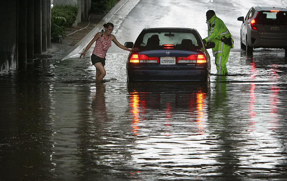 A California Highway Patrol officer and a passer-by assist a stranded motorist in the flooded 14th Street underpass in Riverside, Calif., following a brief downpour.